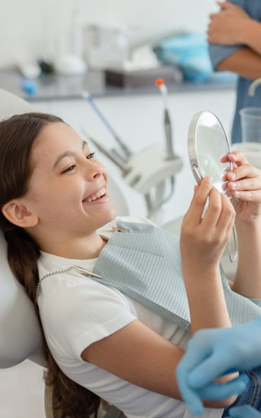 Image of girl looking in the mirror after dental procedure